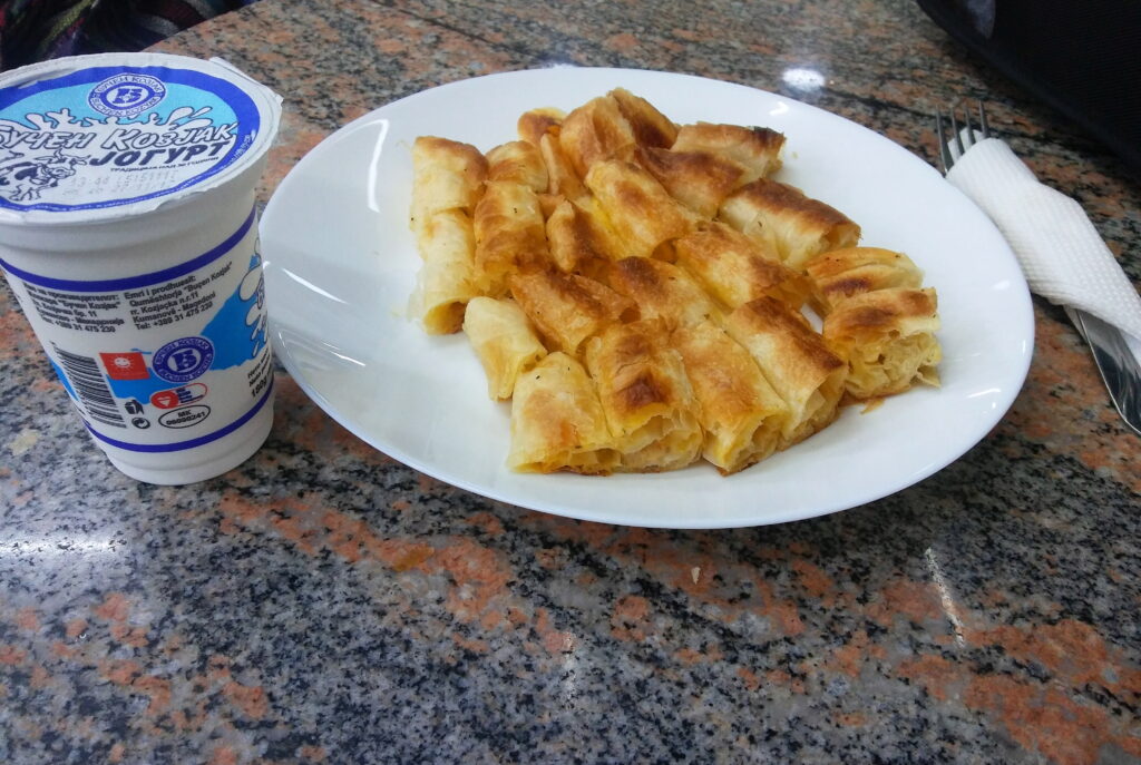 Burek cortado en porciones con un vaso de yogur, como se come en los Balcanes